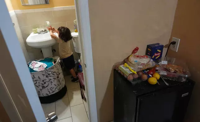 Jakelin Pasedo's three-year-old son washes his hands in the Miami-area motel room where Pasedo and her two children, who all have refugee status, are living, Wednesday, Oct. 22, 2025, after their father requested to be sent back to Venezuela after months in immigration detention. (AP Photo/Rebecca Blackwell)