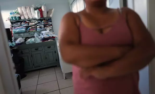 Diapers and clothes fill the shelves of the apartment in South Florida where Guatemalan migrant Amavilia, 31, front, lives with her two children and a roommate, after her partner Edgar was detained days after their son's birth and deported to Guatemala, Wednesday, Oct. 8, 2025. (AP Photo/Rebecca Blackwell)