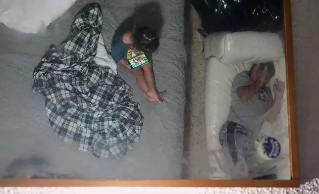 Two brothers are reflected in a ceiling mirror as they pass the time in the Miami-area motel room where they are living with their pregnant mother Yaoska after their father was deported to Nicaragua, Thursday, Nov. 13, 2025. (AP Photo/Rebecca Blackwell)