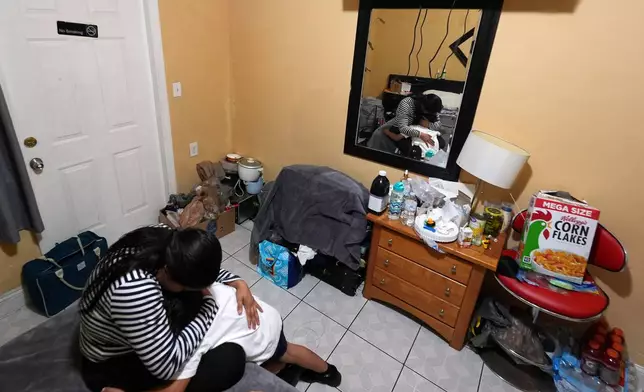 Jakelin Pasedo, 39, hugs her five-year-old son inside the Miami-area motel room where she lives with her two children, who all have refugee status, Wednesday, Oct. 22, 2025, after their father requested to be sent back to Venezuela after months in immigration detention. (AP Photo/Rebecca Blackwell)
