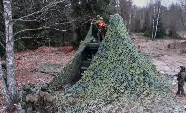In this image made from video provided by Russian Defense Ministry Press Service on Monday, Dec. 29, 2025, Russian solders camouflage one of the trucks of the Russia's Oreshnik missile system with a net during training in an undisclosed location in Belarus. (Russian Defense Ministry Press Service via AP)