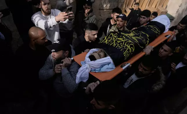 Palestinian men carry Ahmad Ziyoud, draped in the flag of the Islamic Jihad militant group, during his funeral in Silat al-Harithiya, near Jenin, in the West Bank, Sunday, Dec. 21, 2025. (AP Photo/Majdi Mohammad)