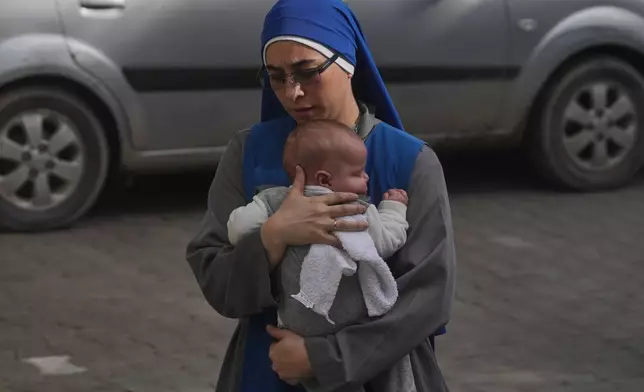 A nun holds a baby as she walks to attend Christmas Eve Mass at the Holy Family Catholic Church in Gaza City, Sunday, Dec. 21, 2025. (AP Photo/Jehad Alshrafi)