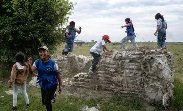 Young Indigenous guards play on the walls of an old military defense barrier made of sandbags, remnants of the military occupation in the area July, 19, 2025, in the Lopez Adentro reserve in Caloto, Colombia. (AP Photo/Nadège Mazars, File)
