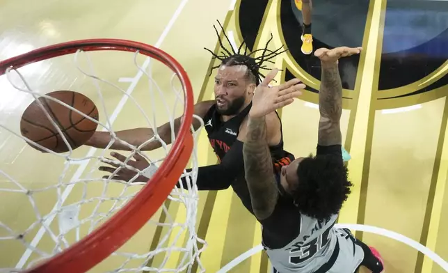 New York Knicks guard Jalen Brunson, left, shoots the ball past San Antonio Spurs forward Julian Champagnie (30) during an NBA Cup championship basketball game, Tuesday, Dec. 16, 2025, in Las Vegas. (Kirby Lee/Pool Photo via AP)