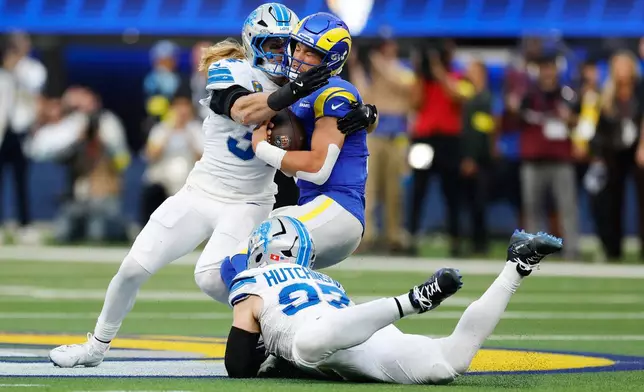Los Angeles Rams quarterback Matthew Stafford is tackled by Detroit Lions middle linebacker Alex Anzalone, top left, and defensive end Aidan Hutchinson (97) during the first half of an NFL football game Sunday, Dec. 14, 2025, in Inglewood, Calif. (AP Photo/Caroline Brehman)