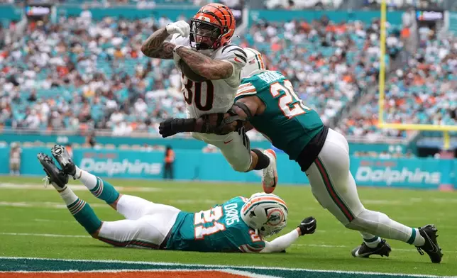 Cincinnati Bengals running back Chase Brown (30) breaks a tackle by Miami Dolphins linebacker Jordyn Brooks (20) for a touchdown during the second half of an NFL football game Sunday, Dec. 21, 2025, in Miami Gardens, Fla. (AP Photo/Lynne Sladky)