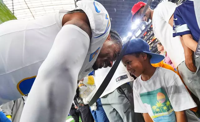 Los Angeles Chargers free safety Derwin James (3) talks to his son Derwin James Jr. before an NFL football game against the Dallas Cowboys, Sunday, Dec. 21, 2025, in Arlington, Texas. (AP Photo/Julio Cortez)