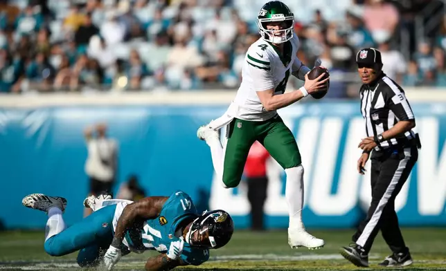 New York Jets quarterback Brady Cook (4) runs with the ball against Jacksonville Jaguars defensive end Josh Hines-Allen (41) during the second half of an NFL football game, Sunday, Dec. 14, 2025, in Jacksonville, Fla. (AP Photo/Phelan M. Ebenhack)