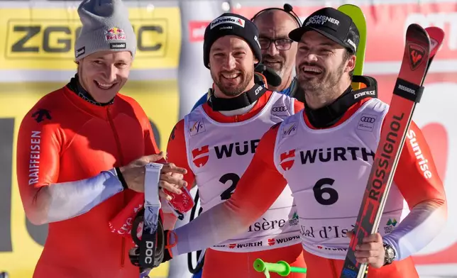 Switzerland's Loic Meillard, right, winner of an alpine ski, men's World Cup giant slalom event, poses with fellow-countrymen second placed Luca Aerni, second from right, and third placed Marco Odermatt, in Val d'Isere, France, Saturday Dec. 13, 2025. (AP Photo/Giovanni Auletta)