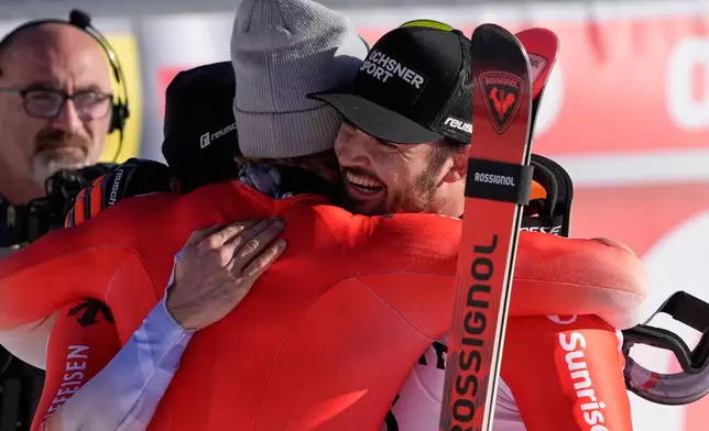 Switzerland's Loic Meillard, right, winner of an alpine ski, men's World Cup giant slalom event, celebrates with fellow-countrymen second placed Luca Aerni and third placed Marco Odermatt, center, in Val d'Isere, France, Saturday Dec. 13, 2025. (AP Photo/Giovanni Auletta)
