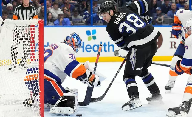 New York Islanders goaltender Ilya Sorokin (30) stops a shot by Tampa Bay Lightning left wing Brandon Hagel (38) during the second period of an NHL hockey game Saturday, Dec. 6, 2025, in Tampa, Fla. (AP Photo/Chris O'Meara)