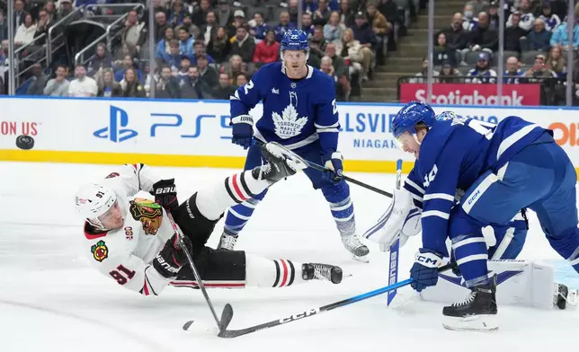 Chicago Blackhawks forward Frank Nazar (91) gets knocked down by Toronto Maple Leafs defenceman Morgan Rielly (44) during the first period of an NHL hockey game in Toronto, Tuesday, Dec. 16, 2025. (Nathan Denette/The Canadian Press via AP)