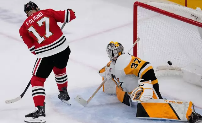 Chicago Blackhawks left wing Nick Foligno, left, scores against Pittsburgh Penguins goaltender Arturs Silovs during the second period of an NHL hockey game in Chicago, Sunday, Dec. 28, 2025. (AP Photo/Nam Y. Huh)