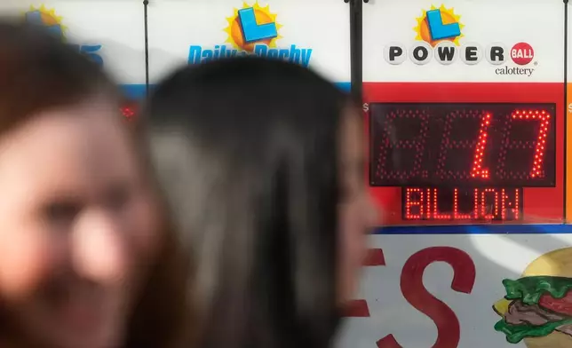 Pedestrians walk past a sign showing the Powerball jackpot of over one billion dollars at Rossi's Deli in San Francisco, Wednesday, Dec. 24, 2025. (AP Photo/Jeff Chiu)
