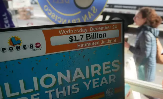 A pedestrian walks past a sign showing the Powerball jackpot of over one billion dollars at Rossi's Deli in San Francisco, Wednesday, Dec. 24, 2025. (AP Photo/Jeff Chiu)
