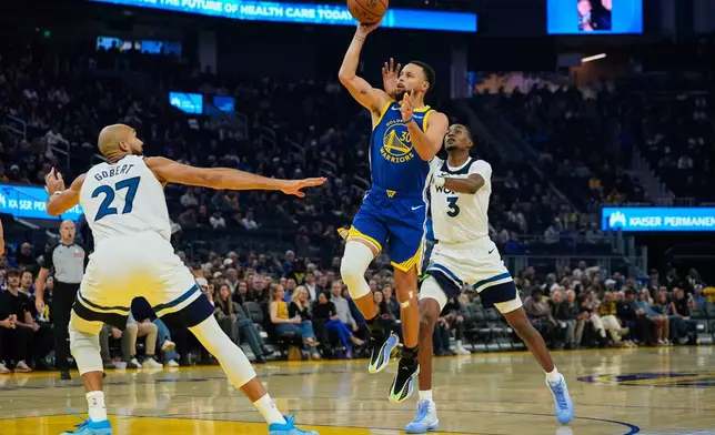 Golden State Warriors guard Stephen Curry (30) shoots between Minnesota Timberwolves center Rudy Gobert (27) and forward Jaden McDaniels (3) during the first half of an NBA basketball game, Friday, Dec. 12, 2025, in San Francisco. (AP Photo/Godofredo A. Vásquez)