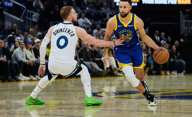 Golden State Warriors guard Stephen Curry (30) moves the ball while defended by Minnesota Timberwolves guard Donte Divincenzo (0) during the first half of an NBA basketball game, Friday, Dec. 12, 2025, in San Francisco. (AP Photo/Godofredo A. Vásquez)