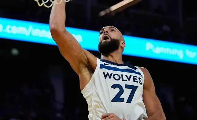 Minnesota Timberwolves center Rudy Gobert (27) shoots while defended by Golden State Warriors guard Stephen Curry (30) during the second half of an NBA basketball game, Friday, Dec. 12, 2025, in San Francisco. (AP Photo/Godofredo A. Vásquez)
