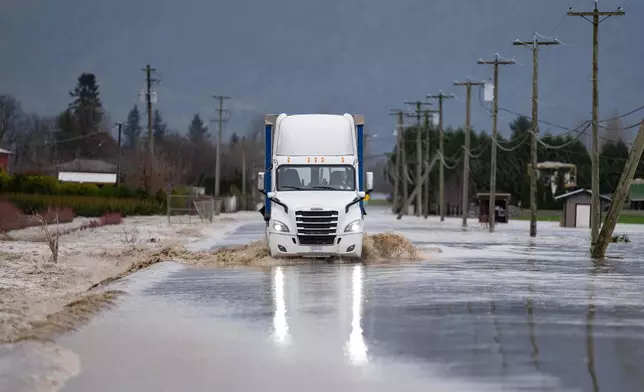 A semi-truck crosses a flooded street in Abbotsford, British Columbia, on Thursday, Dec. 11, 2025. (Ethan Cairns/The Canadian Press via AP)