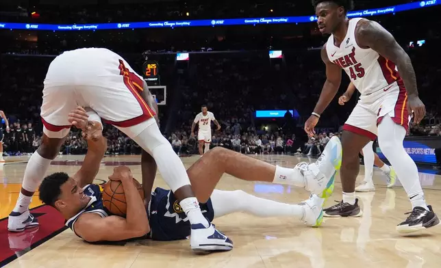 Denver Nuggets forward Spencer Jones (21) falls to the court as he goes for the ball against Miami Heat center Bam Adebayo, left, during the first half of an NBA basketball game, Monday, Dec. 29, 2025, in Miami. (AP Photo/Lynne Sladky)