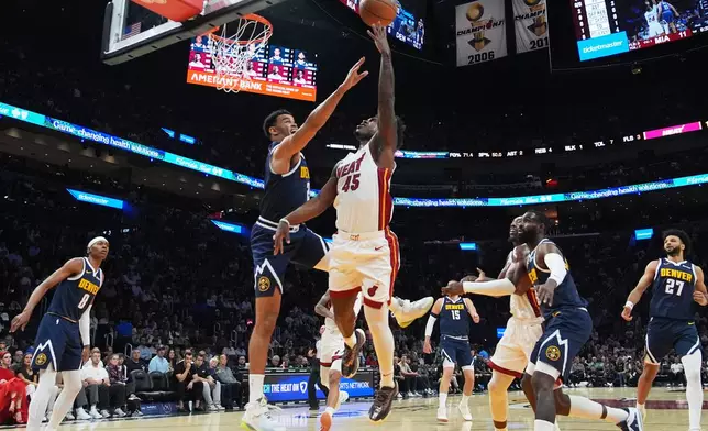 Miami Heat guard Davion Mitchell (45) goes to the basket as Denver Nuggets forward Spencer Jones, left, center, defends during the first half of an NBA basketball game, Monday, Dec. 29, 2025, in Miami. (AP Photo/Lynne Sladky)