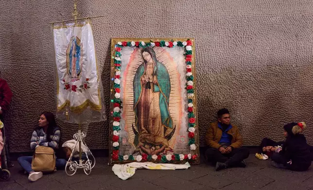 Pilgrims rest next to framed image of the Virgin of Guadalupe outside the Basilica of Guadalupe, in Mexico City, Thursday, Dec. 11, 2025, the day before her feast day. (AP Photo/Claudia Rosel)