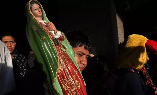 A pilgrim carrying a statue of the Virgin of Guadalupe exits the Basilica of Our Lady of Guadalupe after a Mass in Mexico City, on her feast day, Friday, Dec. 12, 2025. (AP Photo/Claudia Rosel)
