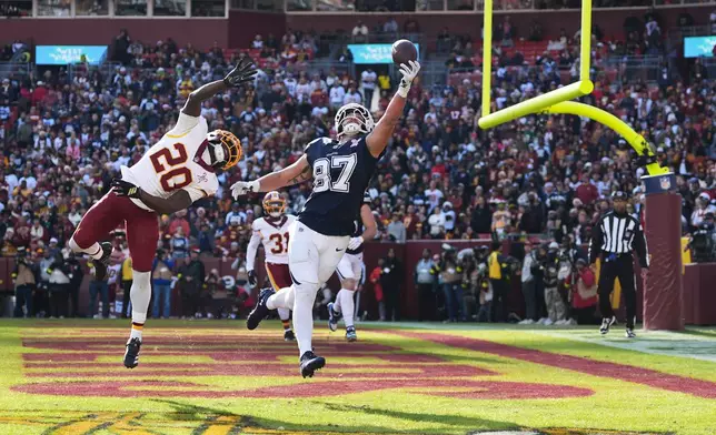 Dallas Cowboys tight end Jake Ferguson (87) catches a touchdown pass as Washington Commanders safety Quan Martin (20) defends during the first half an NFL football game Thursday, Dec. 25, 2025, in Landover, Md. (AP Photo/Stephanie Scarbrough)
