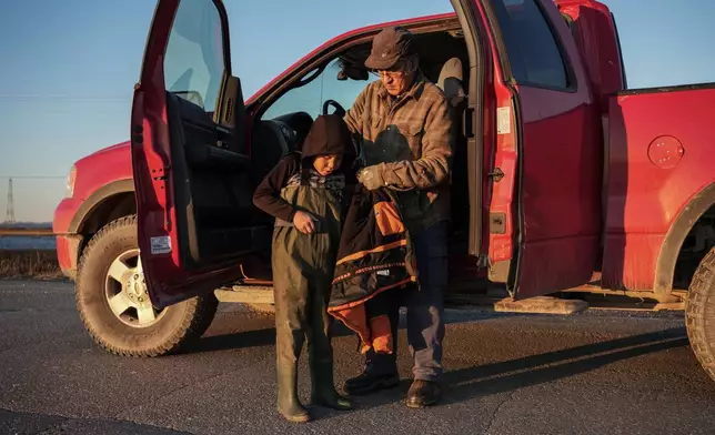Roswell Schaeffer, an Inupiaq hunter and fisher, helps his great-grandson James Schaeffer, 7, into waders while hunting Friday, Sept. 26, 2025. (AP Photo/Annika Hammerschlag)