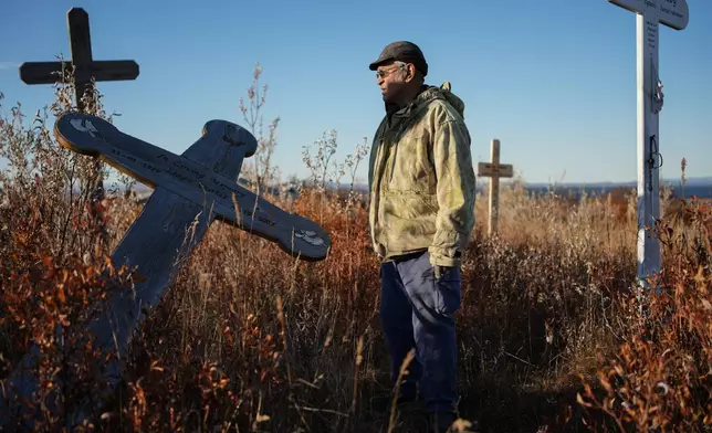 Roswell Schaeffer, an Inupiaq hunter and fisher, visits the cemetery where thawing permafrost has caused grave markers to tilt in Kotzebue, Alaska, Friday, Sept. 26, 2025. (AP Photo/Annika Hammerschlag)