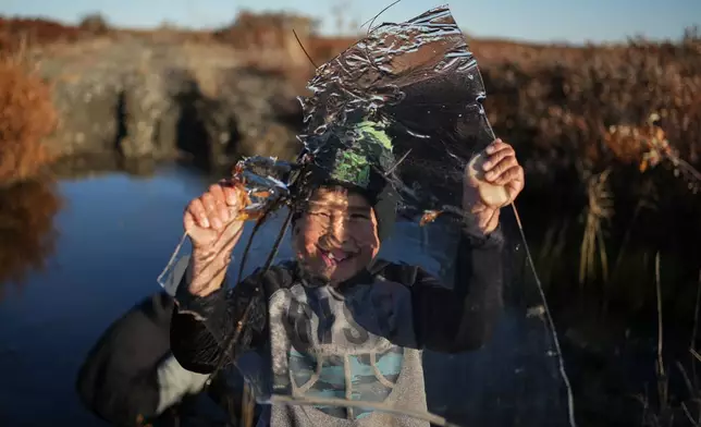 James Schaeffer, 7, plays with a slab of ice taken from a pond that formed on a warped road caused by thawing permafrost in Kotzebue, Alaska, Friday, Sept. 26, 2025. (AP Photo/Annika Hammerschlag)