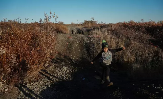 James Schaeffer, 7, plays on a road where thawing permafrost has caused the ground to warp in Kotzebue, Alaska, Friday, Sept. 26, 2025. (AP Photo/Annika Hammerschlag)