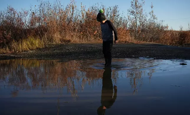 James Schaeffer, 7, plays on a road where thawing permafrost has caused the ground to warp in Kotzebue, Alaska, Friday, Sept. 26, 2025. (AP Photo/Annika Hammerschlag)