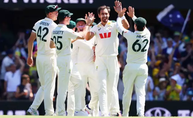 Australia's Mitchell Starc, centre, celebrates with teammate the wicket of England's Ben Duckett during the second Ashes cricket test match between Australia and England in Brisbane, Thursday, Dec. 4, 2025.. (AP Photo/Tertius Pickard)