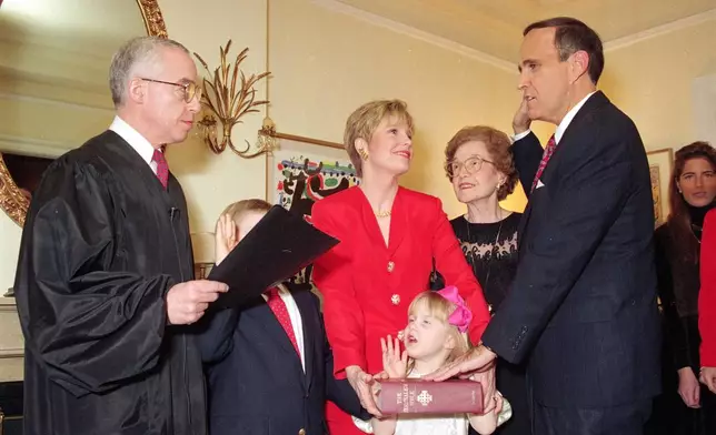 FILE - Republican Rudolph Giuliani, right, is symbolically sworn-in as New York City Mayor by U.S. District Court Judge Michael B. Mukasey, left, during a private ceremony in New York, Friday, Dec. 31, 1993. Giuliani's wife Donna Hanover, center, stands with their children Andrew, 7, and Caroline, 4 and Giuliani's mother Helen looks on. (AP Photo/Ed Bailey, File)