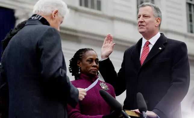 FILE - Mayor-elect Bill de Blasio, right, takes the oath of office administered by former President Bill Clinton, left, as de Blasio's wife, Chirlane McCray, center, holds the bible for her husband during his public inauguration ceremony at City Hall in New York, on Jan. 1, 2014. (AP Photo/Seth Wenig, File)