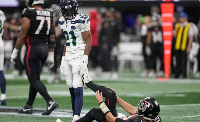Seattle Seahawks cornerback Devon Witherspoon looks down at Atlanta Falcons quarterback Kirk Cousins after a tackle during the first half of an NFL football game, Sunday, Dec. 7, 2025, in Atlanta. (AP Photo/Brynn Anderson)