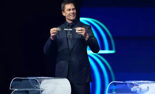 Former NFL player Tom Brady holds up the name of England during the draw for the 2026 soccer World Cup at the Kennedy Center in Washington, Friday, Dec. 5, 2025. (Jia Haocheng/Pool Photo via AP)