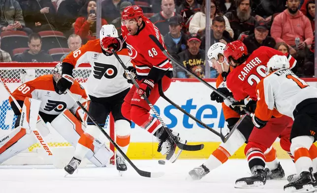 Carolina Hurricanes' Jordan Martinook (48) jumps over a shot by teammate William Carrier (28) for a goal during the first period of an NHL hockey game against the Philadelphia Flyers in Raleigh, N.C., Sunday, Dec. 14, 2025. (AP Photo/Ben McKeown)