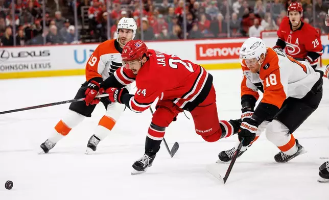 Carolina Hurricanes' Seth Jarvis (24) and Philadelphia Flyers' Rodrigo Abols (18) chase the puck during the second period of an NHL hockey game in Raleigh, N.C., Sunday, Dec. 14, 2025. (AP Photo/Ben McKeown)