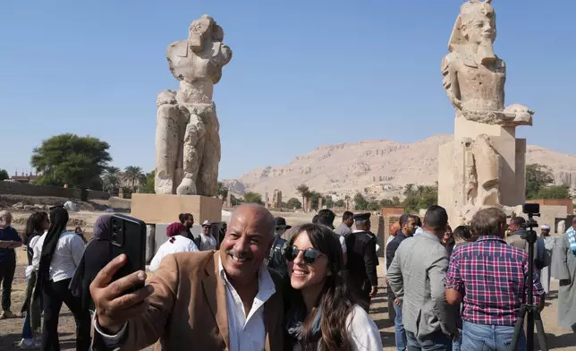 Visitors take photos with the two giant reassembled alabaster statues of Pharoah Amenhotep III, in the southern city of Luxor, Egypt, Sunday, Dec. 14, 2025. (AP Photo/Amr Nabil)