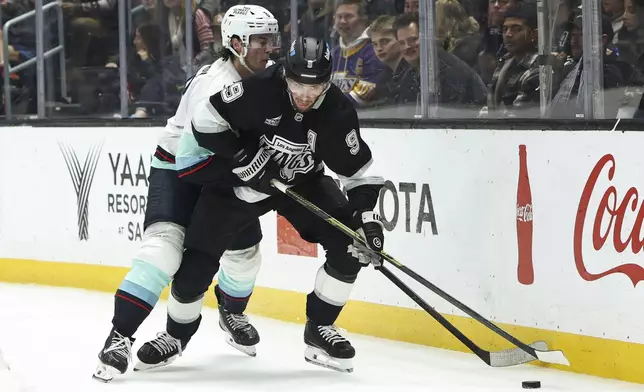 Los Angeles Kings right wing Adrian Kempe (9) battles for the puck against Seattle Kraken defenseman Cale Fleury, back, during the second period of an NHL hockey game, Tuesday, Dec. 23, 2025, in Los Angeles. (AP Photo/Jessie Alcheh)