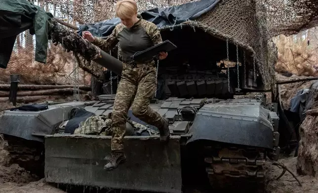 A Ukrainian soldier from the Khartia brigade, callsign Muza, jumps down from a tank following a demonstration for The Associated Press, Thursday, Nov. 6, 2025, in Kharkiv Oblast, Ukraine. (AP Photo/Julia Demaree Nikhinson)