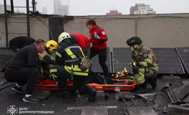 In this photo provided by the Ukrainian Emergency Service, emergency services personnel evacuate a local citizen wounded after a Russian missiles attack in Dnipro, Ukraine, Monday, Dec. 1, 2025. (Ukrainian Emergency Service via AP)