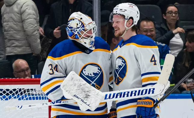 Buffalo Sabres goalie Alex Lyon, left, and Bowen Byram share a laugh after defeating the Vancouver Canucks in an NHL hockey game in Vancouver, British Columbia, on Thursday, Dec. 11, 2025. (Rich Lam/The Canadian Press via AP)