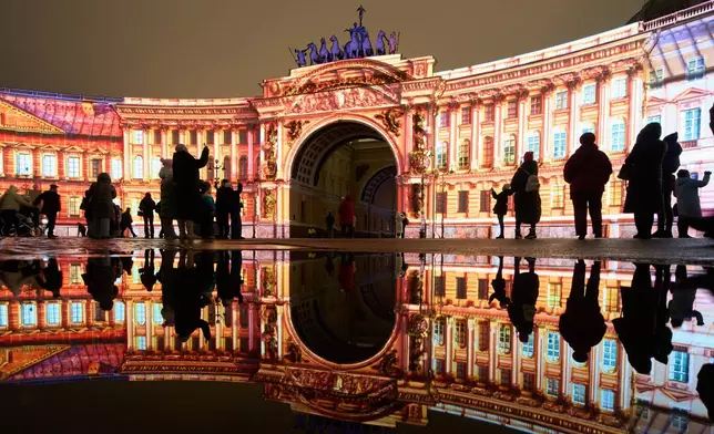 People watch a multimedia light show during the "Country of Light" festival at the Palace Square, in St. Petersburg, Russia, Sunday, Dec. 7, 2025. (AP Photo/Dmitri Lovetsky)