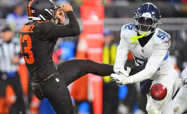 Tennessee Titans linebacker James Williams Sr. (52) blocks a punt attempt by Cleveland Browns' Corey Bojorquez (13) in the second half of an NFL football game in Cleveland, Sunday, Dec. 7, 2025. (AP Photo/David Richard)