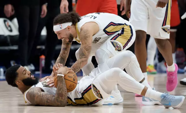 New Orleans Pelicans guards Jose Alvarado, top, and Saddiq Bey, bottom, celebrate as they take the lead in the final seconds of overtime against the Houston Rockets during an NBA basketball game in New Orleans, Thursday, Dec. 18, 2025. (AP Photo/Matthew Hinton)