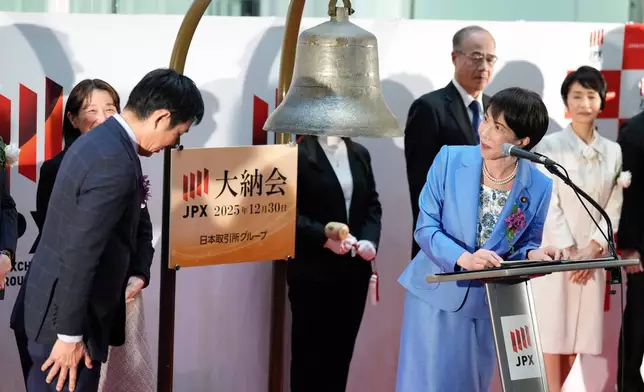 Japan's Prime Minister Sanae Takaichi, right, delivers a speech as Hajime Moriyasu, left, the head coach of Japanese national soccer team, bows during a ceremony to mark the last trading day of the year on the Tokyo Stock ExchangeTuesday, Dec. 30, 2025, in Tokyo. (AP Photo/Eugene Hoshiko)